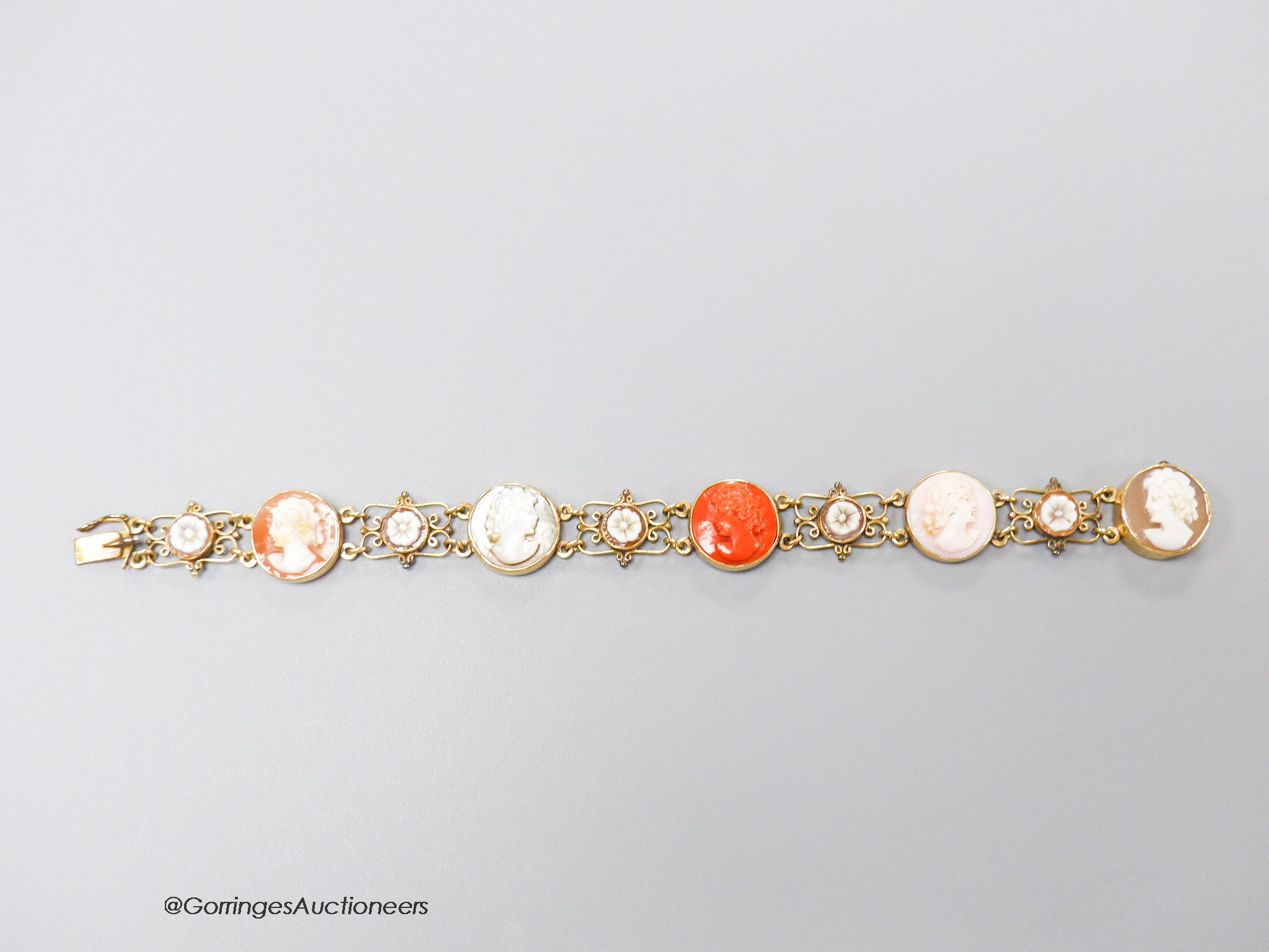 A 14k yellow metal, multi carved cameo and flowerhead set bracelet, including paua shell, shell and coral, carved with the busts of ladies, to dexter and sinister, 16.5cm, gross weight 13.5 grams.